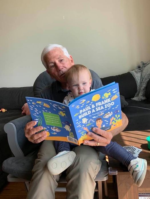 A Grandpa Reads A Story Book To His Granddaughter